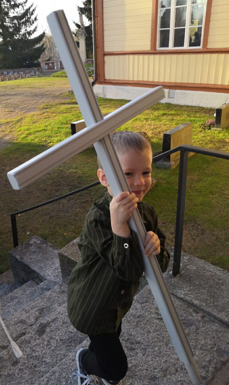 Pieni poika kantaa kokoistaa puuristiä kirkonportaita ylös